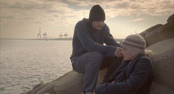 Movie still from “Candy” (2006), directed by Neil Armfield – A man and a woman sitting on top of a rock near the water; Medium shot, Over the shoulder angle