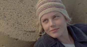 Movie still from “Candy” (2006), directed by Neil Armfield – A woman wearing a hat is smiling for the camera; Close Up shot, Over the shoulder angle