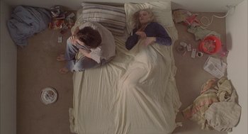 Movie still from “Candy” (2006), directed by Neil Armfield – A man and a woman laying in a bed; Wide shot, Overhead angle