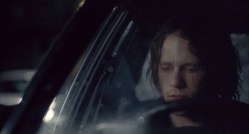Movie still from “Candy” (2006), directed by Neil Armfield – A man sitting in the driver's seat of a car; Close Up shot, Over the shoulder angle
