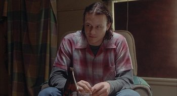 Movie still from “Candy” (2006), directed by Neil Armfield – A man sitting in a chair holding a glass of beer; Close Up shot, High angle