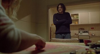 Movie still from “Candy” (2006), directed by Neil Armfield – A man standing in front of a mirror in a room; Medium shot, Over the shoulder angle