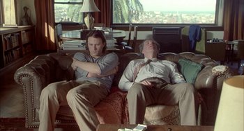 Movie still from “Candy” (2006), directed by Neil Armfield – Two men sitting on a couch with their arms crossed; Medium shot, High angle