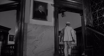 Movie still from “Cape Fear” (1962), directed by J. Lee Thompson – A black and white photo of a man in a suit and hat; Wide shot, Low angle