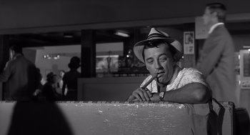 Movie still from “Cape Fear” (1962), directed by J. Lee Thompson – A black and white photo of a man smoking a cigarette; Medium shot, Over the shoulder angle