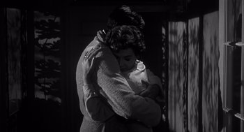 Movie still from “Cape Fear” (1962), directed by J. Lee Thompson – A man and a woman hugging in a dark room; Medium shot, Low angle