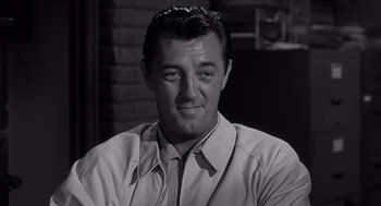 Movie still from “Cape Fear” (1962), directed by J. Lee Thompson – A black - and - white photo of a man smiling; Close Up shot, Over the shoulder angle