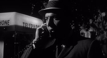 Movie still from “Cape Fear” (1962), directed by J. Lee Thompson – A black and white photo of a man talking on a phone; Close Up shot, Low angle