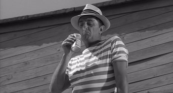 Movie still from “Cape Fear” (1962), directed by J. Lee Thompson – A black and white photo of a man drinking from a can; Medium shot, Low angle
