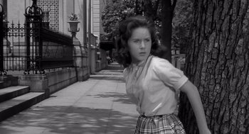 Movie still from “Cape Fear” (1962), directed by J. Lee Thompson – A young woman walking down a sidewalk in a school uniform; Medium shot, Low angle