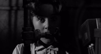 Movie still from “Cape Fear” (1962), directed by J. Lee Thompson – A young girl looking into the camera in a dimly - lit room; Close Up shot, High angle
