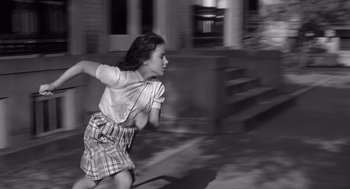Movie still from “Cape Fear” (1962), directed by J. Lee Thompson – A young woman running in a street with a building in the background; Medium shot, High angle