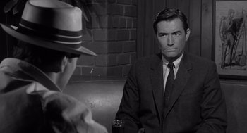 Movie still from “Cape Fear” (1962), directed by J. Lee Thompson – A black and white photo of a man in a suit and hat; Medium shot, Over the shoulder angle