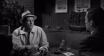 Movie still from “Cape Fear” (1962), directed by J. Lee Thompson – A black and white photo of a man sitting at a table; Medium shot, Over the shoulder angle