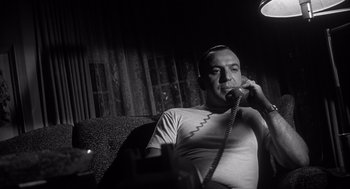Movie still from “Cape Fear” (1962), directed by J. Lee Thompson – A man sitting on a couch talking on a phone; Close Up shot, Low angle