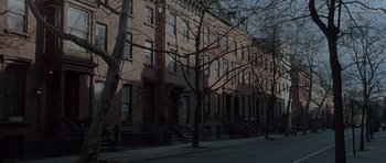 Movie still from “Capote” (2005), directed by Bennett Miller – A row of brown brick buildings on a street corner; Extreme Wide shot, High angle