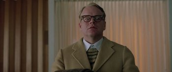 Movie still from “Capote” (2005), directed by Bennett Miller – A man in a suit and tie wearing glasses; Close Up shot, Low angle