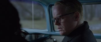Movie still from “Capote” (2005), directed by Bennett Miller – A man with glasses sitting in a car; Close Up shot, Over the shoulder angle