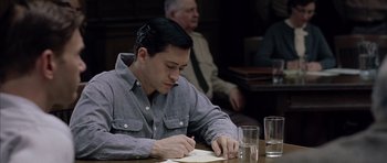 Movie still from “Capote” (2005), directed by Bennett Miller – A man sitting at a table writing on a piece of paper; Medium shot, High angle
