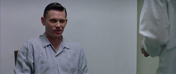 Movie still from “Capote” (2005), directed by Bennett Miller – A man in a gray shirt is standing in front of a white wall; Close Up shot, Over the shoulder angle