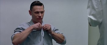 Movie still from “Capote” (2005), directed by Bennett Miller – A man is tying his tie while looking at the camera; Close Up shot, Over the shoulder angle