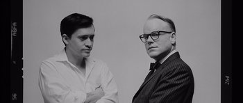 Movie still from “Capote” (2005), directed by Bennett Miller – Two men standing next to each other in front of a white wall; Close Up shot, Low angle