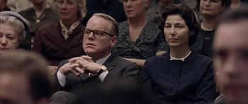 Movie still from “Capote” (2005), directed by Bennett Miller – A man and a woman sitting next to each other in front of other people; Close Up shot, Over the shoulder angle