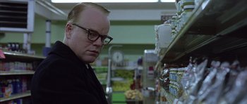Movie still from “Capote” (2005), directed by Bennett Miller – A man with glasses looking at a shelf in a grocery store; Close Up shot, Low angle