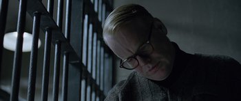 Movie still from “Capote” (2005), directed by Bennett Miller – A man wearing glasses looking down at his face; Close Up shot, Over the shoulder angle