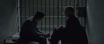 Movie still from “Capote” (2005), directed by Bennett Miller – Two men sitting next to each other in front of a jail cell; Medium shot, Over the shoulder angle