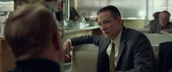 Movie still from “Capote” (2005), directed by Bennett Miller – A man wearing a suit and tie sitting in front of another man; Close Up shot, Over the shoulder angle