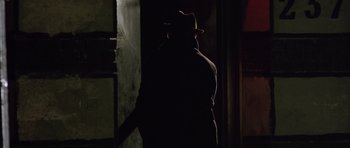 Movie still from “Capote” (2005), directed by Bennett Miller – A man wearing a hat standing next to a wall; Close Up shot, Low angle
