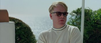Movie still from “Capote” (2005), directed by Bennett Miller – A man with blonde hair wearing a white shirt and sunglasses; Close Up shot, Over the shoulder angle