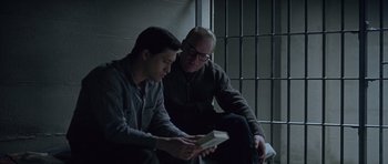 Movie still from “Capote” (2005), directed by Bennett Miller – Two men sitting next to each other in front of a jail cell; Medium shot, High angle