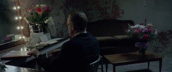 Movie still from “Capote” (2005), directed by Bennett Miller – A man sitting at a table in front of a laptop computer; Medium shot, Over the shoulder angle