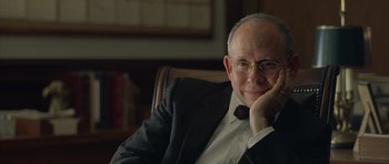 Movie still from “Capote” (2005), directed by Bennett Miller – An older man sitting in a chair with his hand on his chin; Close Up shot, Over the shoulder angle