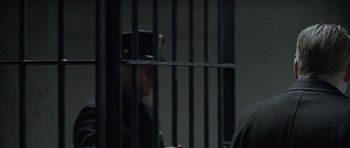 Movie still from “Capote” (2005), directed by Bennett Miller – A person in a jail cell looking through the bars; Close Up shot, Over the shoulder angle