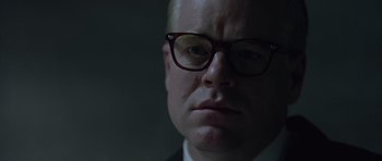 Movie still from “Capote” (2005), directed by Bennett Miller – A person wearing a suit and glasses; Close Up shot, Over the shoulder angle