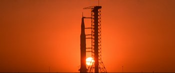 Movie still from “Capricorn One” (1977), directed by Peter Hyams – The sun is setting behind a rocket in the sky; Extreme Wide shot, Low angle