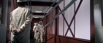Movie still from “Capricorn One” (1977), directed by Peter Hyams – A group of people in spacesuits walking down a hallway; Wide shot, Low angle