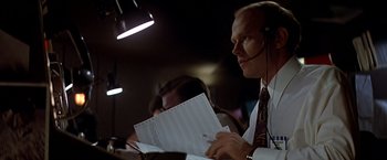 Movie still from “Capricorn One” (1977), directed by Peter Hyams – A man with a headset on holding papers; Close Up shot, Low angle