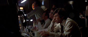 Movie still from “Capricorn One” (1977), directed by Peter Hyams – A group of men sitting at a table with cups; Medium shot, High angle