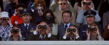 Movie still from “Capricorn One” (1977), directed by Peter Hyams – A group of people watching something with binoculars; Medium shot, Low angle