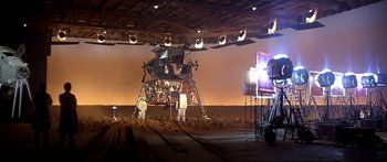Movie still from “Capricorn One” (1977), directed by Peter Hyams – An image of a man working on an object in the desert; Extreme Wide shot, High angle