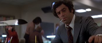 Movie still from “Capricorn One” (1977), directed by Peter Hyams – A man sitting at a table smoking a cigarette; Close Up shot, Low angle