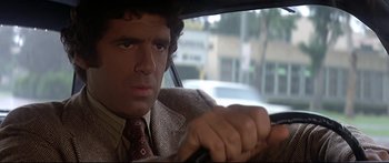 Movie still from “Capricorn One” (1977), directed by Peter Hyams – A man sitting in the drivers seat of a car; Close Up shot, Over the shoulder angle