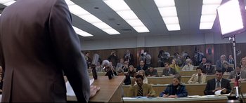 Movie still from “Capricorn One” (1977), directed by Peter Hyams – A man standing at a podium in front of a crowd of people; Wide shot, Over the shoulder angle