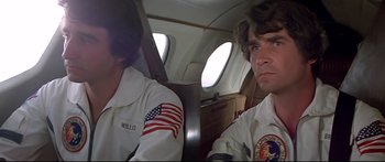 Movie still from “Capricorn One” (1977), directed by Peter Hyams – Two men sitting in the back of an airplane; Close Up shot, Low angle