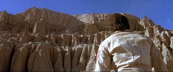 Movie still from “Capricorn One” (1977), directed by Peter Hyams – A person standing in front of a cliff; Wide shot, Low angle