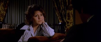 Movie still from “Capricorn One” (1977), directed by Peter Hyams – A woman sitting on a couch in front of a window; Close Up shot, Over the shoulder angle